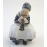 A Royal Copenhagen figure of a seated Amager girl knitting, model no. 1314, designed by Lotte