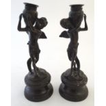 A pair of 20thC figural spelter candlesticks, each formed as an angel holding a vase. Approx. 11"