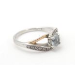 A silver ring with 9ct gold detail set with central white stone flanked by bands of chip set