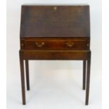 An 18thC oak bureau on stand, with a fall opening to show graduated drawers and a central door,