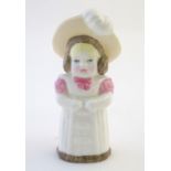 A Royal Worcester figural candle snuffer modelled as a young girl wearing a hat, titled Feathered