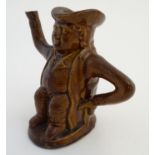A treacle glazed Toby jug teapot formed as a seated man, his arms forming the handle and spout.