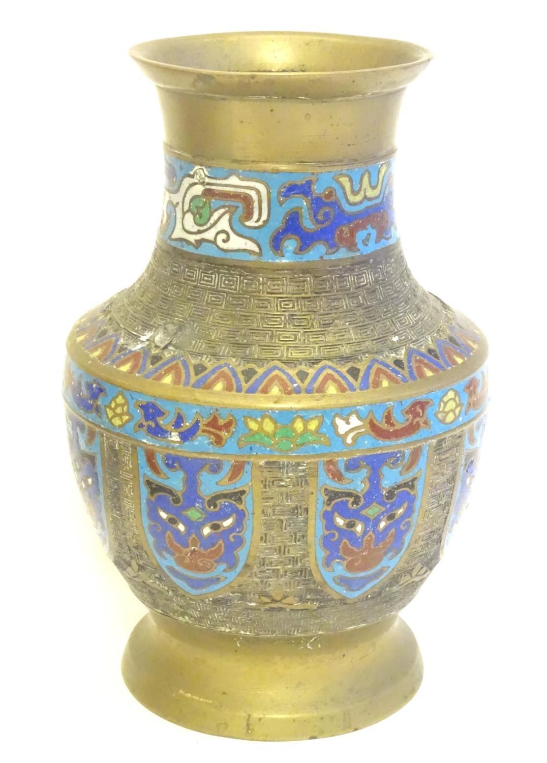 A Japanese brass vase of baluster form with Cloisonné mask and shield decoration to sides. Approx. 9