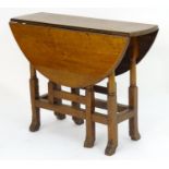 A late 19thC oak gateleg table, having drop flaps opening to form an oval table top and standing