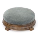 A Victorian mahogany footstool with a circular upholstered top studded detail above four shaped