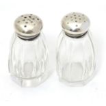 A pair of glass pepperettes with silver tops marked Sterling. Approx 2" high Please Note - we do not