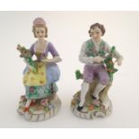 A pair of German Sitzendorf porcelain florist figures, a gentleman and lady, each seated on a