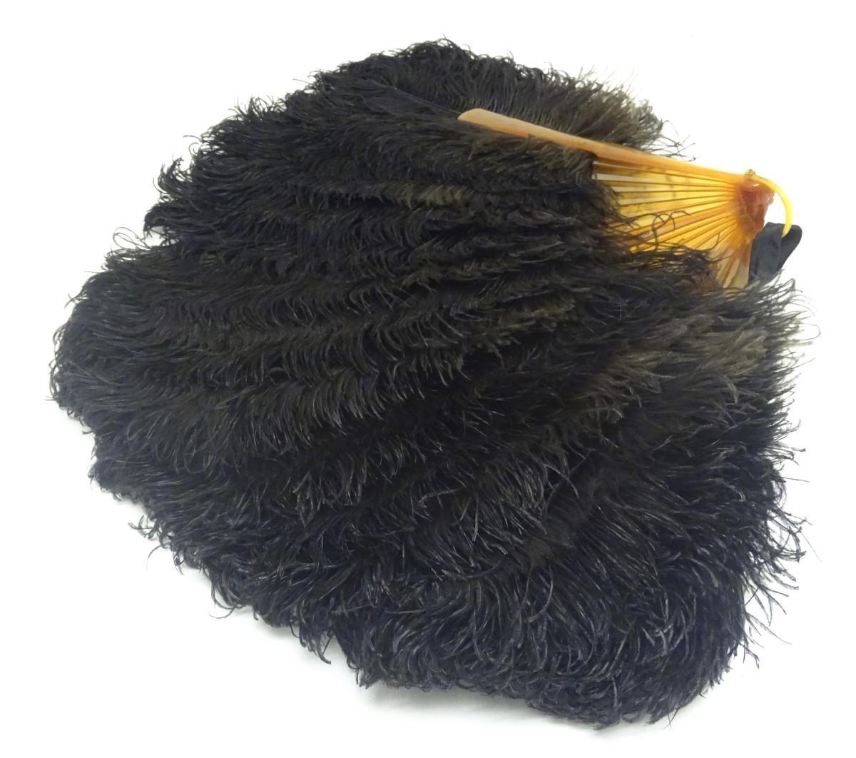 An early 20thC ostrich feather fan, with 18 sticks, the front stick with white metal detail set with