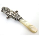 A silver rattle handle with comical lion to centre and mother of pearl teether. Hallmarked