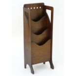 An Arts & Crafts Glasgow school oak magazine rack with pierced holes to the frame and with three