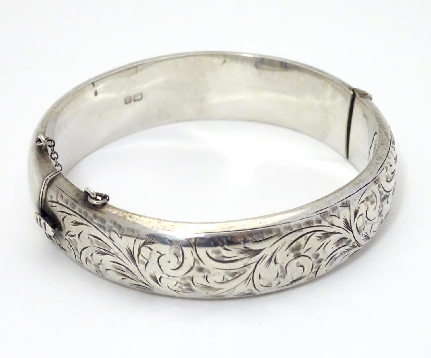 A silver bracelet of bangle form with engraved acanthus scroll decoration. Hallmrked Chester 1952