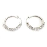 A pair of white metal hoop earrings set with six pear shaped white stones. Stamped 925. Approx. 1"