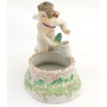 A 19thC Berlin salt modelled as a cherub holding a tankard above a brick well, the interior