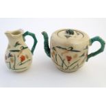 A Japanese teapot and milk jug with hand painted decoration depicting birds and flowers, the handles