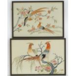 Two oriental silk embroideries depicting stylised golden pheasant birds perched on branches, with