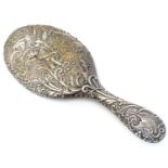 A silver hand mirror with embossed decoration depicting putto amongst foliage with winged insect.