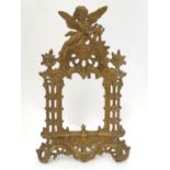An early 20thC cast metal frame of stylised architectural form surmounted by a putto with a lyre.