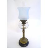 An early 20thC Duplex oil lamp, with opaque glass shade, clear glass reservoir supported by a