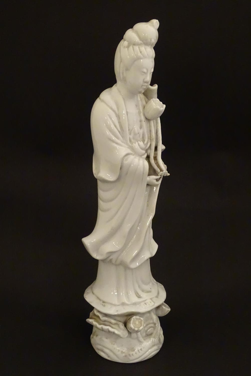 A Chinese blanc de chine figure of Guanyin holding flowers, raised on a base of lotus flowers and - Image 3 of 9