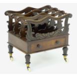 A mid 19thC mahogany canterbury with scrolled and carved dividers with turned supports, having a