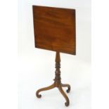 A late 18thC / early 19thC mahogany tilt top table with a turned pedestal base and three scrolled