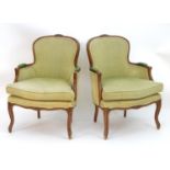 A pair of French Louis XV style armchairs with moulded frames, carved cresting rails and leather