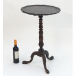A Georgian mahogany tripod wine table with a pie crust top above a turned stem with carved