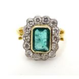 An 18ct gold ring set with central emerald bordered by 14 diamonds. the whole setting 3/4" x 1/2".