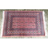 Carpet / Rug : A salmon ground rug decorated with various banded and geometric detail. Approx 65"