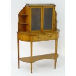 A 19thC satinwood cabinet with a pierced brass gallery above two glazed doors flanked by graduated