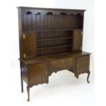 An early 20thC oak dresser with a moulded cornice above a shaped frieze and plate rack flanked by