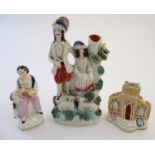 Three items of Staffordshire pottery, to include a figural bud vase, a flatback house and a figure