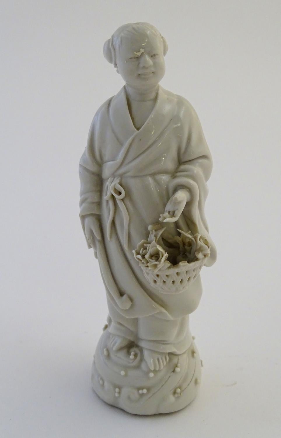 A Chinese blanc de chine depicting the Daoist Immortal figure, Lan Caihe, with a basket of