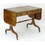 An early 19thC mahogany sofa table with cross banded top and drop flaps, decorative stringing and