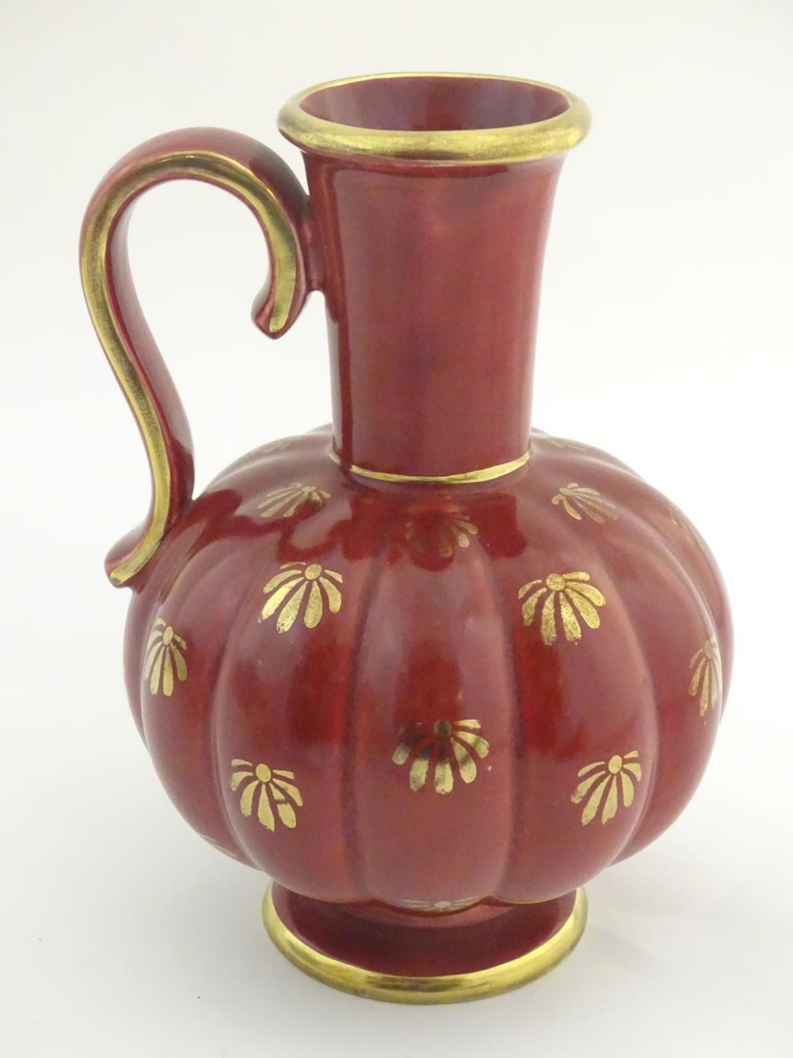 A Swedish single handled vase with a ribbed bulbous body and an elongated neck, with gilt stylised