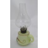 A small glass oil lamp with floral decoration, loop handle and clear glass chimney. 10'' high
