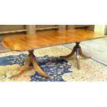 A mid 20thC mahogany pedestal dining table, the two pedestals having three splayed legs