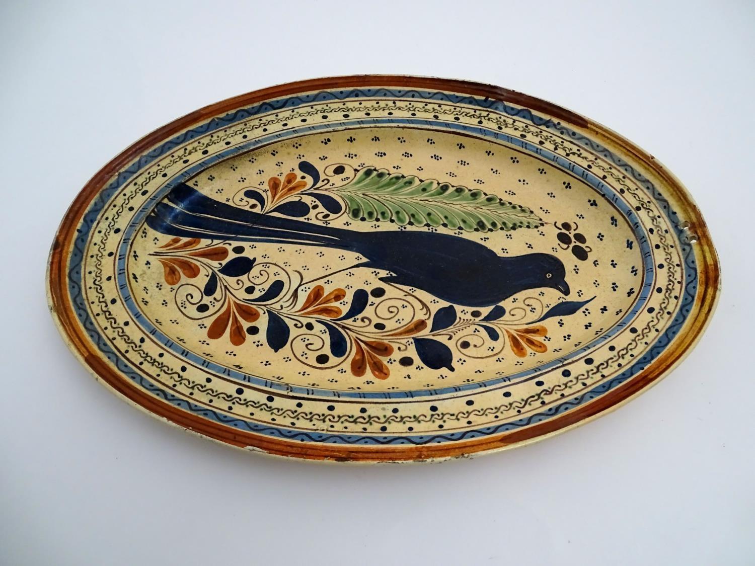 A Swiss terracotta oval pottery dish with hand painted folk art decoration depicting a bird - Image 3 of 6