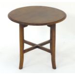 An early 20thC occasional table with a circular mahogany top above four swept legs and cross