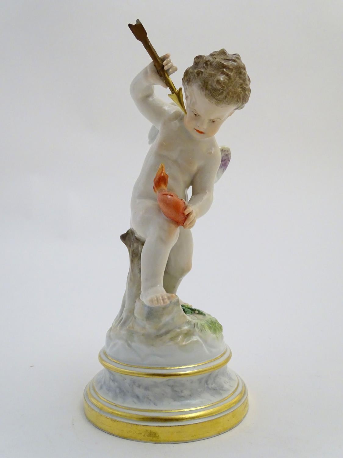 A late 19thC Meissen figure of Cupid holding an arrow and a flaming heart. On a naturalistic base.