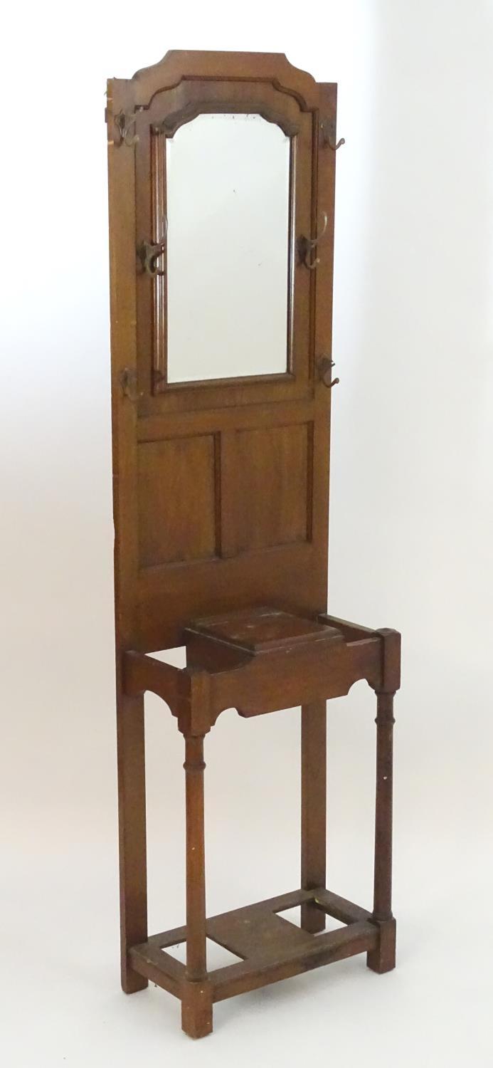 An early 20thC mahogany hall stand with a central bevelled mirror surrounded by ogee mouldings,