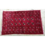 Carpet / Rug : A red ground rug with banded geometric decoration and central repeating medallion and