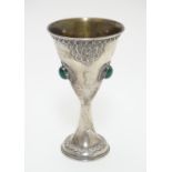 A Continental white metal chalice of conical form with gilded interior and set with three green/