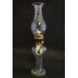 A mid-20thC oil table lamp, the clear glass reservoir forming the base with fluted spirals. 15" tall