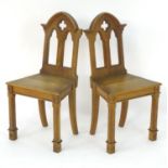 A pair of mid 19thC oak hall chairs with pointed pediments, pierced decoration and carved