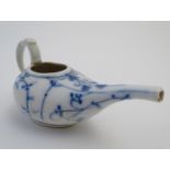 A blue and white pap boat with a stylised floral and foliate design with a handle and spout.