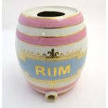 A large ceramic early 20thC public house rum barrel, in white, pink and blue glaze with gilt