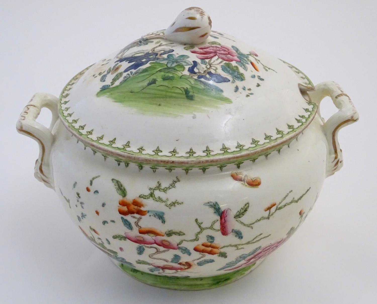 A Chinese tureen and cover with twin handles decorated with a stylised landscape with a tree and