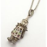 A silver pendant on chain, the pendant formed as an articulated clown, - the clowns coat set with