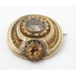 A 19thC yellow metal brooch with engraved decoration and set with two citrine coloured stones, the